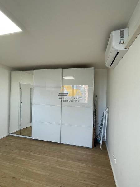 Einzimmerwohnung mit einem Spiegelschrank und einem Boden in Holzoptik.