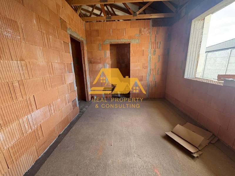 Der Innenraum eines im Bau befindlichen Einfamilienhauses mit freiliegenden Ziegeln und Baumaterialien.