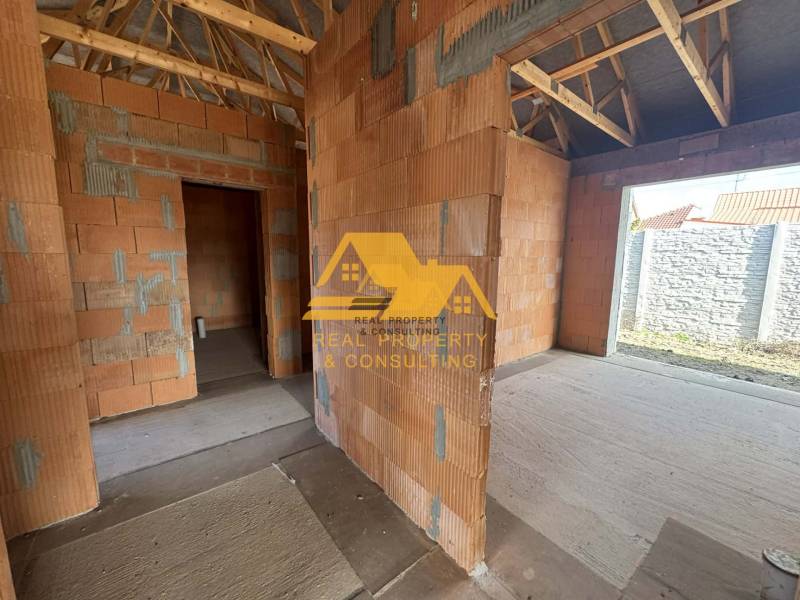 Ein im Bau befindliches Einfamilienhaus mit Blick auf unverputzte Wände und einem hölzernen Dachstuhl.