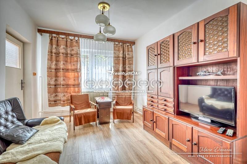 Wohnzimmer mit Holzmöbeln, Sofa und Fernseher in einem Einfamilienhaus.