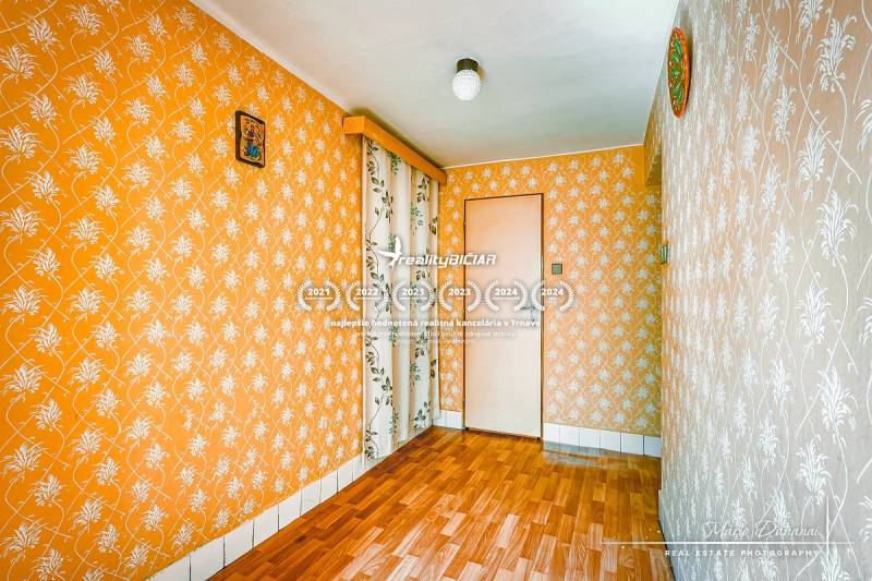Ein Zimmer in einem Einfamilienhaus mit orangefarbener Tapete und Parkettboden.