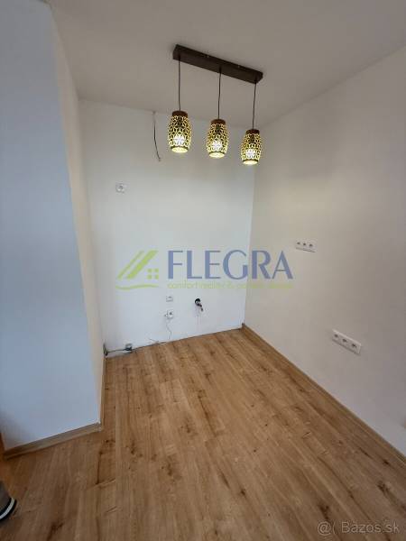 Innenraum einer Einzimmerwohnung mit Holzboden und Hängelampen.