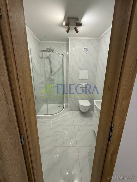 Badezimmer in einer Einzimmerwohnung mit Duschkabine und Keramikfliesen.