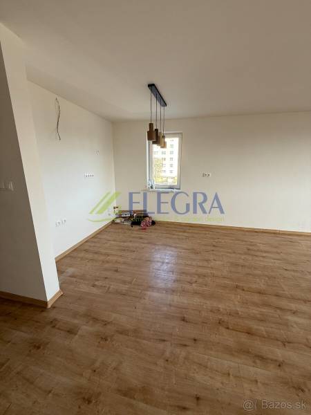 Ein Zimmer einer 2-Zimmer-Wohnung mit einem Boden in Holzoptik und hängenden Leuchten.