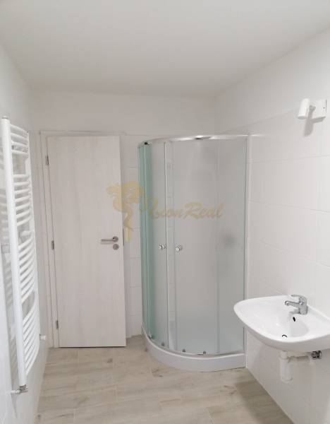 Badezimmer mit Toilette, Dusche und Boden mit Holzdekor in einem Einfamilienhaus.