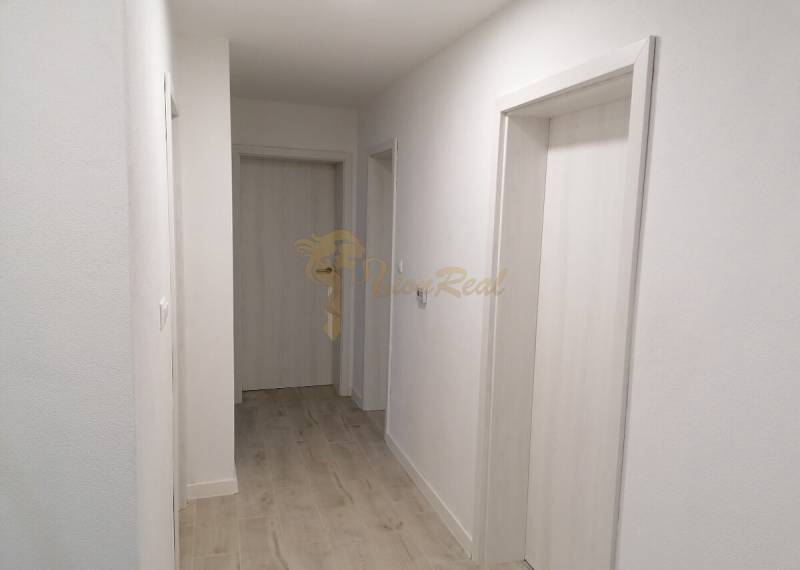 Ein schmaler Flur in einem Einfamilienhaus mit weißen Wänden und einem Boden in Holzoptik.