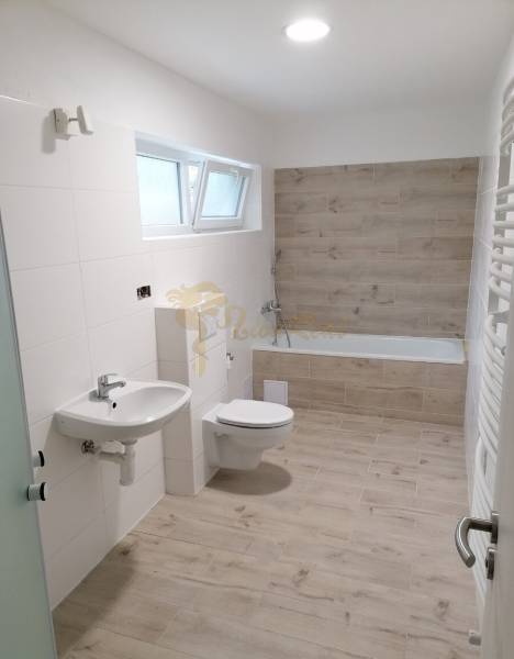 Badezimmer in einem Einfamilienhaus mit Holzboden, Badewanne und Waschbecken.