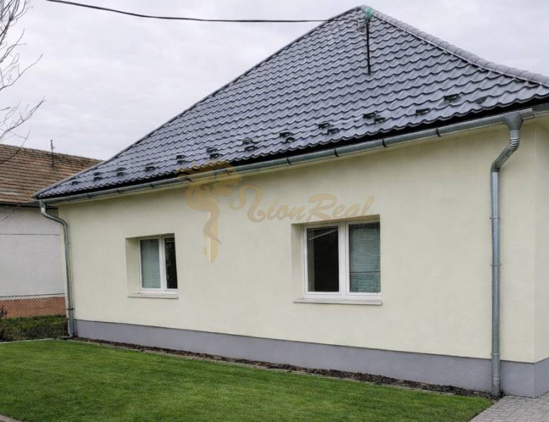 Ein Einfamilienhaus in Bernolákovo mit Rasen, grauem Dach und heller Fassade.