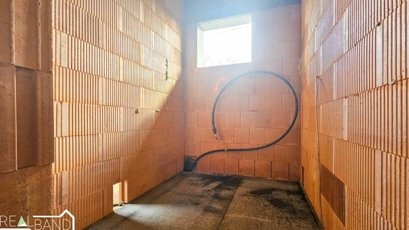 Unvollendeter Innenraum in einem Einfamilienhaus mit Sichtmauerwerk und einer Öffnung für ein Fenster.