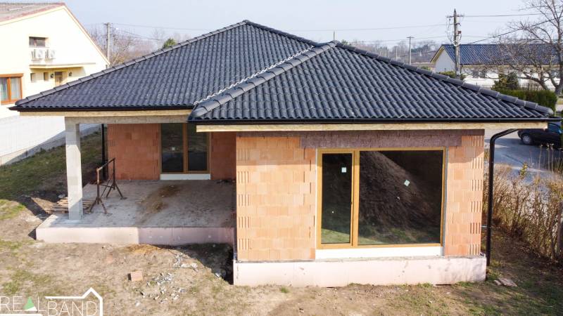 Einfamilienhaus in Pavlice im Bau, Ziegelfassade, dunkles Dach, große Fenster.