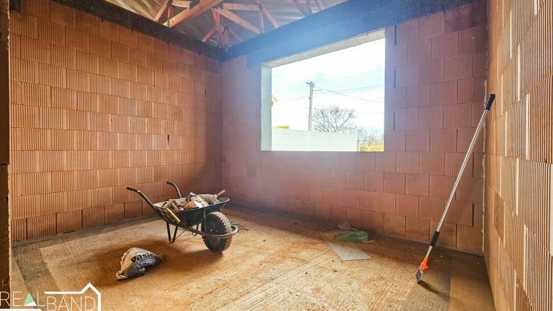 Interieurräume in einem Einfamilienhaus mit Ziegelwänden, einer Schubkarre und Werkzeugen.