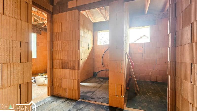 Der Innenraum eines im Bau befindlichen Einfamilienhauses mit Ziegelwänden und Dachträgern.