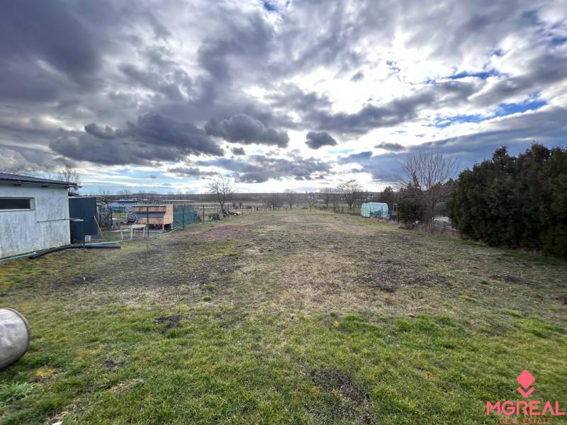 Grundstück bei einem Einfamilienhaus in Zbehy mit Blick auf einen weitläufigen Garten und den Himmel.