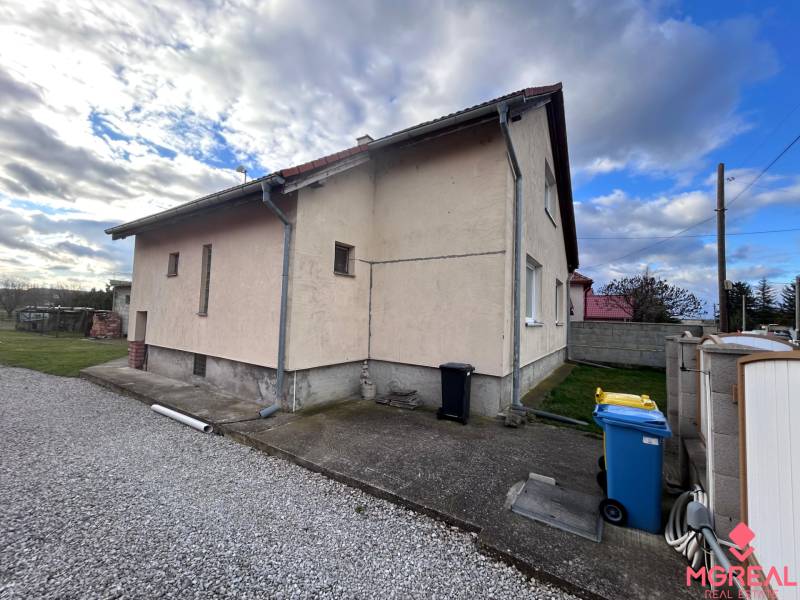 Ein Einfamilienhaus in Zbehy mit einer Nebenstraße, einem Rasen und einem blauen Mülleimer.