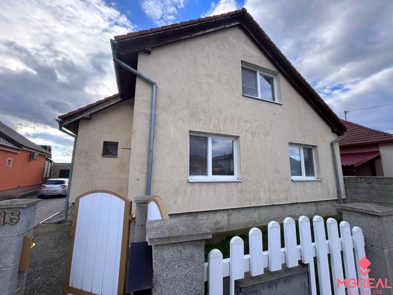 Ein Einfamilienhaus in Zbehy mit einem Schrägdach, einem Zaun und einer Zufahrtsstraße.