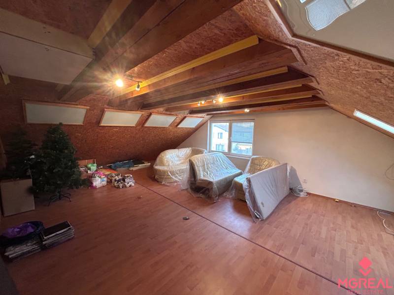 Ein Dachzimmer in einem Einfamilienhaus mit einem Boden in Holzoptik und Dachfenstern.