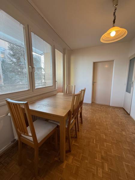 Esszimmer mit Tisch und Stühlen in einer 3-Zimmer-Wohnung, Boden mit Holzdekor.