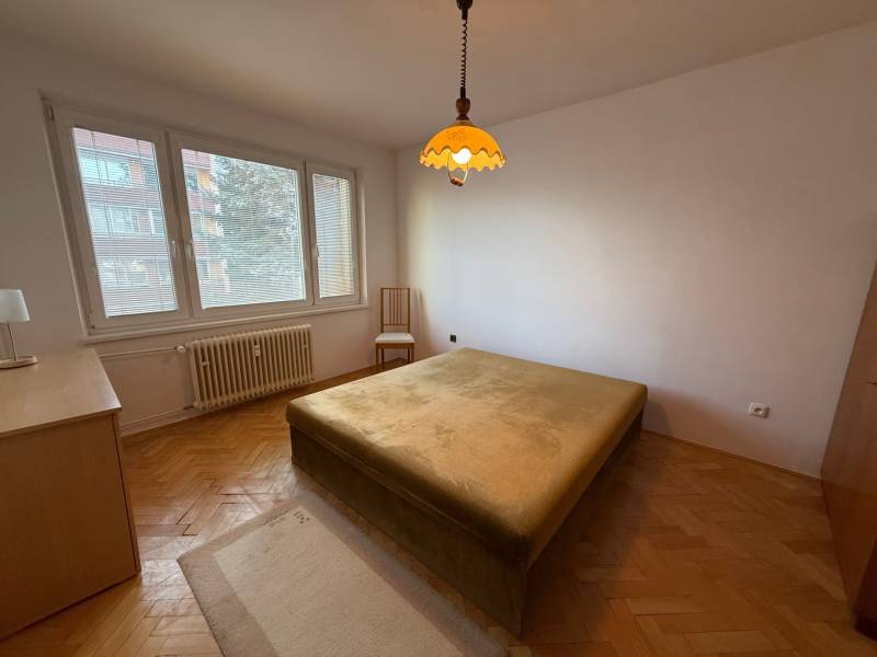 Schlafzimmer in einer 3-Zimmer-Wohnung mit Fenster, Bett und Boden in Holzoptik.