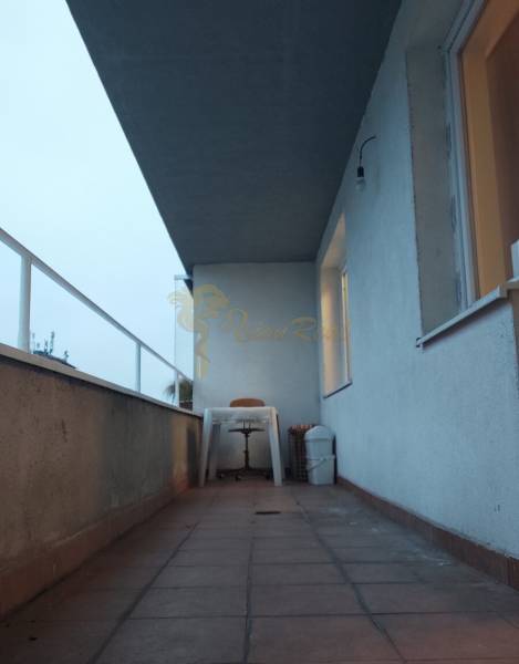 Balkon mit Terrassenfliesen und Kunststoffmöbeln in einer Einzimmerwohnung.