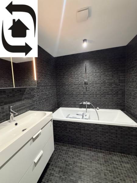 Elegantes Badezimmer mit dunklen Fliesen und Badewanne in einer 4-Zimmer-Wohnung.