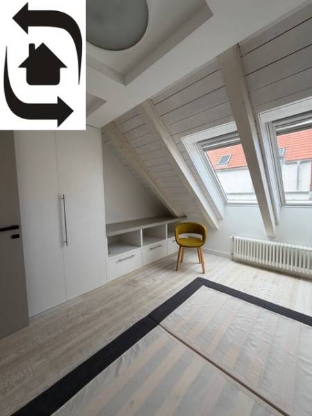 Dachzimmer mit Holzboden, Einbauschrank und gelbem Stuhl.