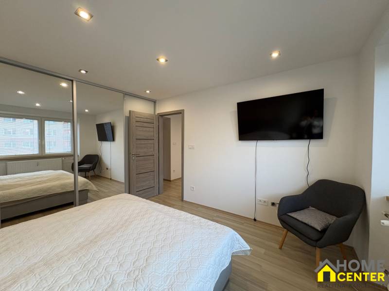 Zweizimmerwohnung mit Fernseher, Kleiderschrank und Holzboden.