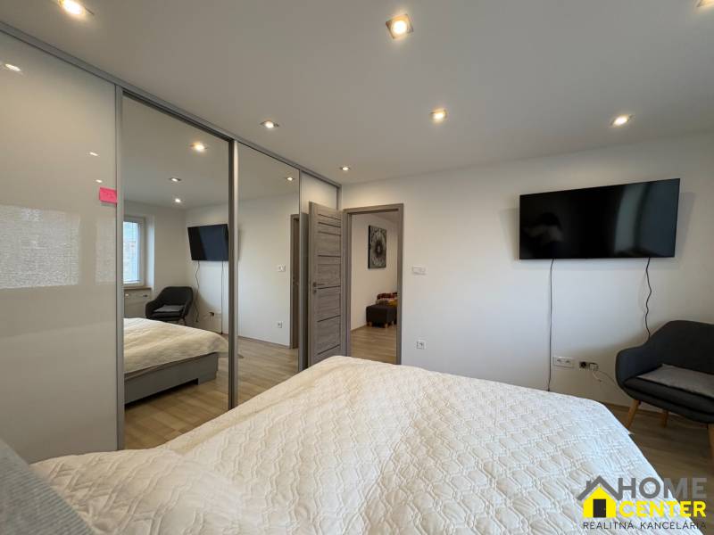 Schlafzimmer in einer 2-Zimmer-Wohnung mit Fernseher, großem Schrank und Holzboden.