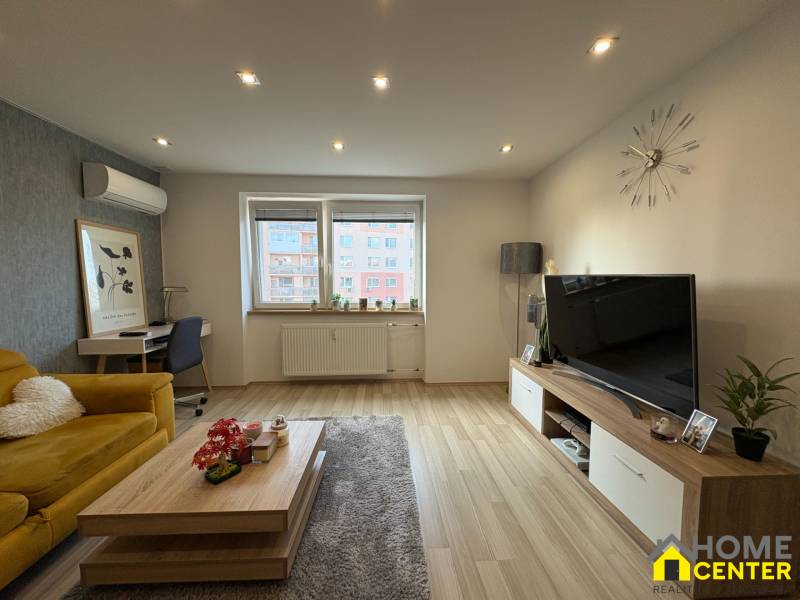 Wohnzimmer in einer 2-Zimmer-Wohnung mit Holzboden, Sofa und Fernseher.