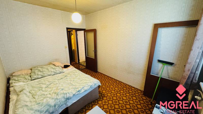 Schlafzimmer mit Teppich, Bett und hellen Wänden in einer 2-Zimmer-Wohnung.