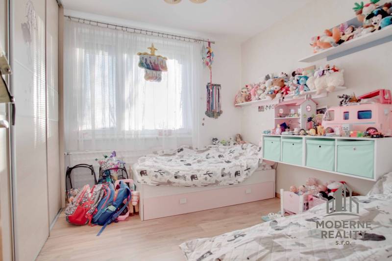 Kinderzimmer in einer 3-Zimmer-Wohnung mit Spielzeug und Bett, Boden mit Holzdekor.