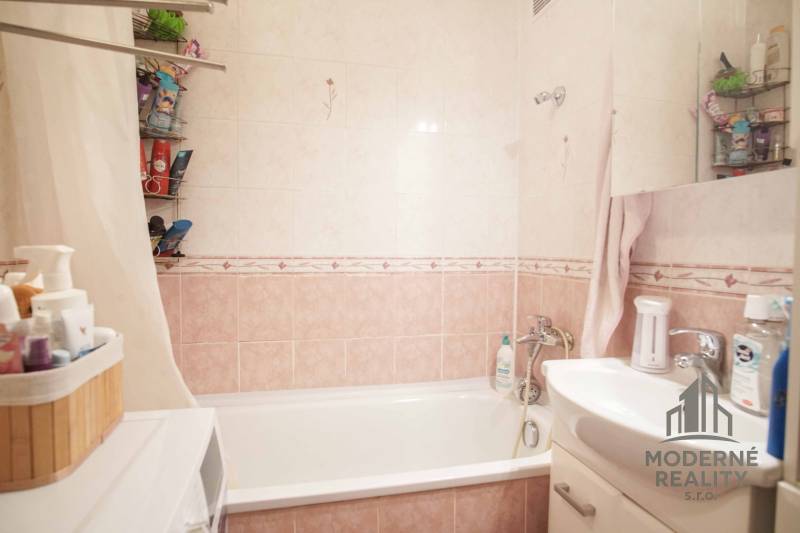 Badezimmer mit Badewanne, Waschbecken und Stauraum in einer 3-Zimmer-Wohnung.