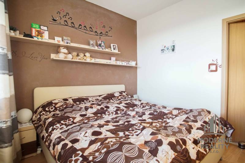 Schlafzimmer in einer 3-Zimmer-Wohnung mit dekorierter Wand und auffälliger Bettwäsche.