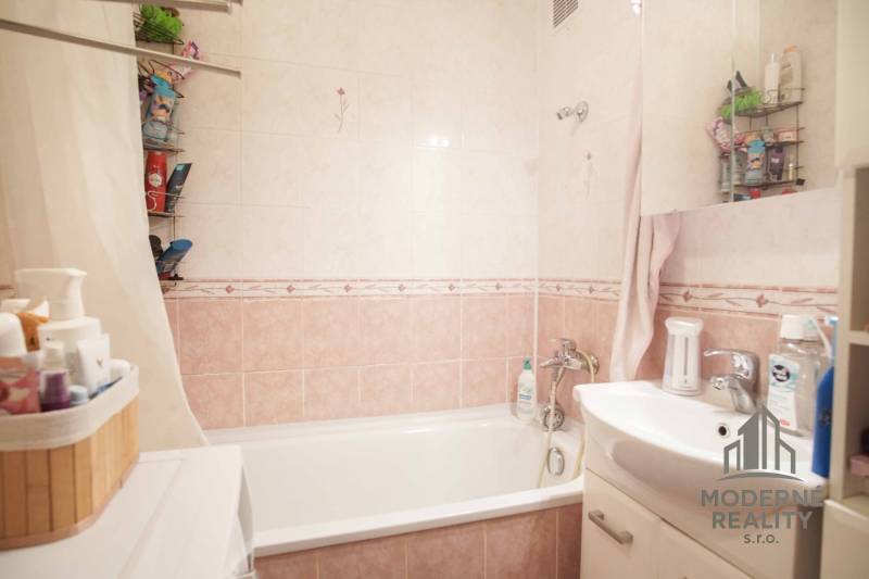 Badezimmer mit Badewanne und Waschbecken in einer 3-Zimmer-Wohnung, Fliesen in sanften Farbtönen.