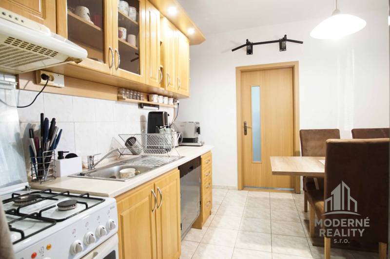 Küche in einer 3-Zimmer-Wohnung mit Holzschränken und Esstisch.