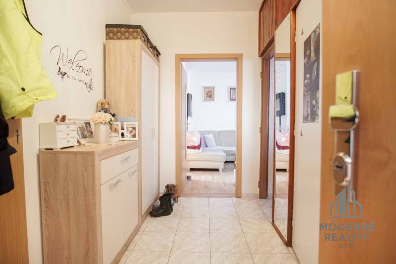 Flur in einer 3-Zimmer-Wohnung mit Fliesenboden und gemütlichen Möbeln in Holzdekor.