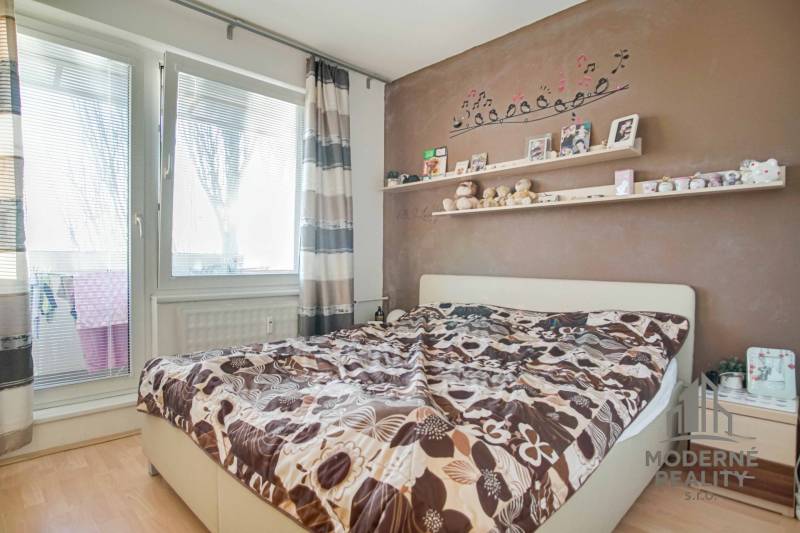 Schlafzimmer in einer 3-Zimmer-Wohnung mit dekorativer Wand, Regal und Bett, Boden mit Holzdekor.