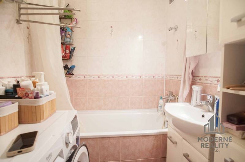 Badezimmer in einer 3-Zimmer-Wohnung mit Badewanne, Waschbecken, Waschmaschine und Stauraum.