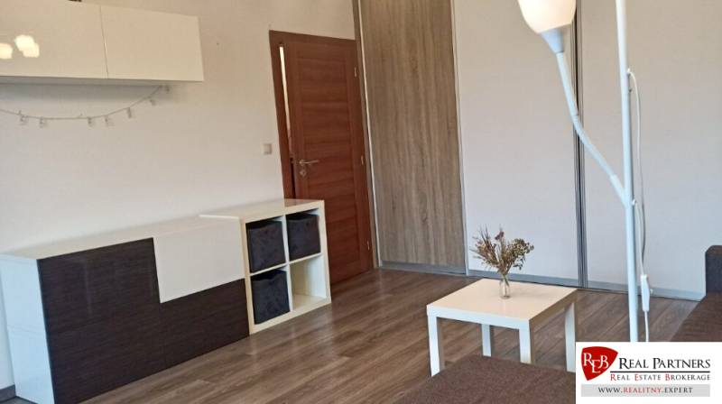 Wohnzimmer in einer Zweizimmerwohnung mit Holzboden und modernen Möbeln.