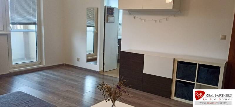 Wohnzimmer in einer Zweizimmerwohnung mit Holzboden und Zugang zum Balkon.