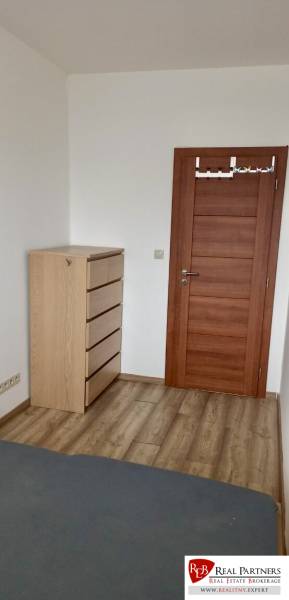 Ein Zimmer in einer 2-Zimmer-Wohnung mit einer Kommode und einem Boden in Holzoptik.