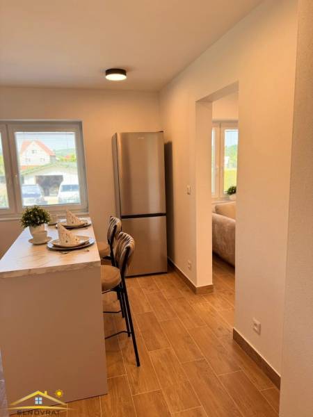 Küche in einer 2-Zimmer-Wohnung mit Bar, Holzboden und Kühlschrank.