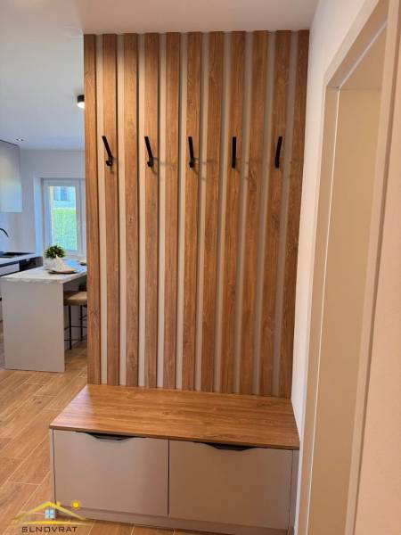 Flur in einer 2-Zimmer-Wohnung mit einer Lamellenwand und einer Kommode mit Stauraum.