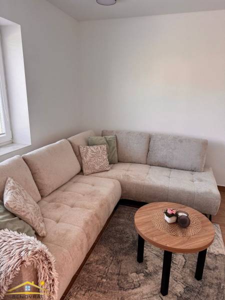 Ein bequemes helles Sofa und ein Tisch mit Dekoration in einer 2-Zimmer-Wohnung.