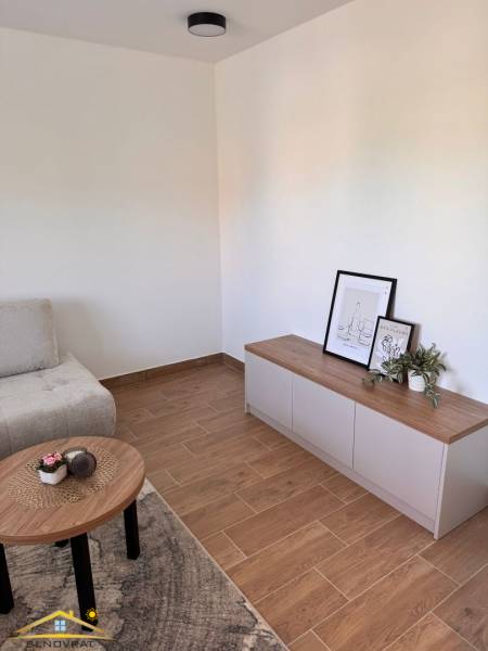 Wohnzimmer in einer 2-Zimmer-Wohnung mit Holzboden und minimalistischem Möbel.