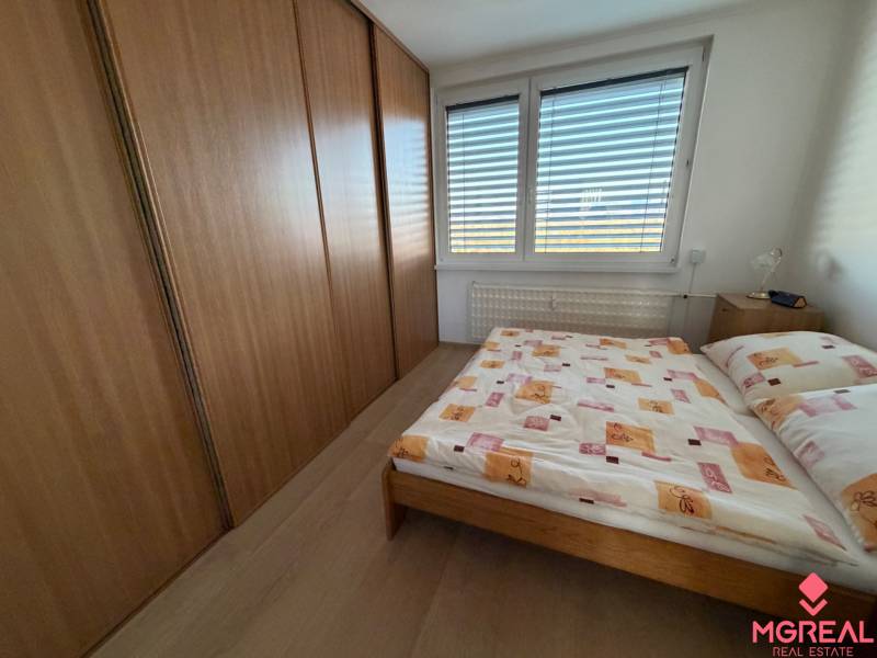 Schlafzimmer in einer 3-Zimmer-Wohnung mit großem Schrank und Bett, Boden mit Holzdekor.