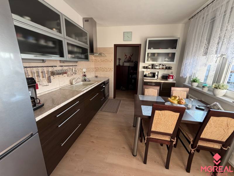 Küche in einer 3-Zimmer-Wohnung mit Küchenzeile und Tisch, Boden mit Holzdekor.