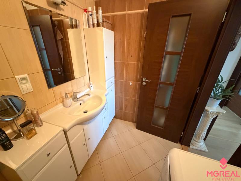 Badezimmer in einer 3-Zimmer-Wohnung mit weißen Möbeln und dunklen Türen.