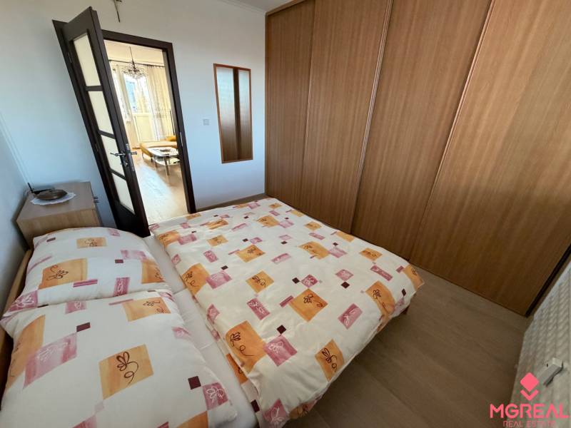 Schlafzimmer in einer 3-Zimmer-Wohnung mit Bett, Einbauschrank und Boden mit Holzdekor.