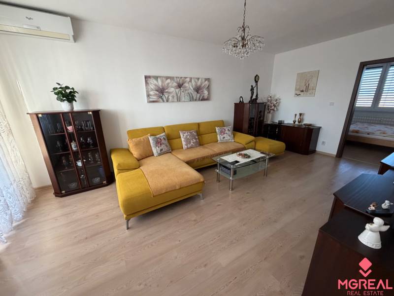 Wohnzimmer mit Holzboden, gelbem Sofa und Glastisch in einer 3-Zimmer-Wohnung.