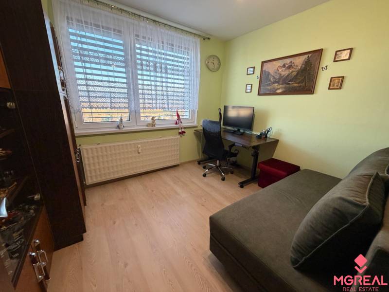 Ein Zimmer mit Holzboden in einer 3-Zimmer-Wohnung, ausgestattet mit einem Sofa und einem Schreibtisch.